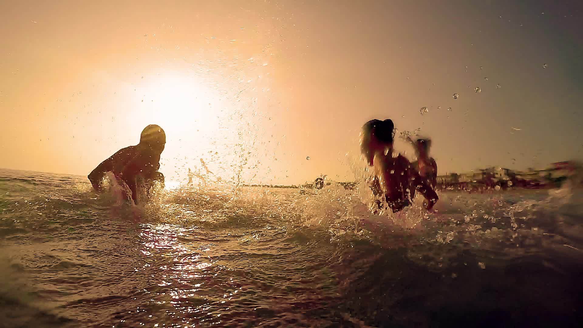 日落时一群幸福的家庭在海滩上飞溅喷水夏天日落视频的预览图