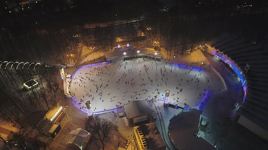 晚上一群人在大型照明溜冰场滑冰以便在圣诞节期间鸟瞰视频的预览图