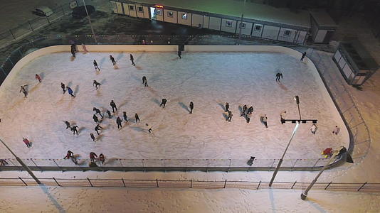 晚上一群人在灯火通明的溜冰场上滑冰鸟瞰无人机视频的预览图