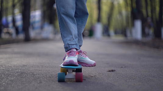 在滑板上收紧双腿在公园里沥青运动视频的预览图