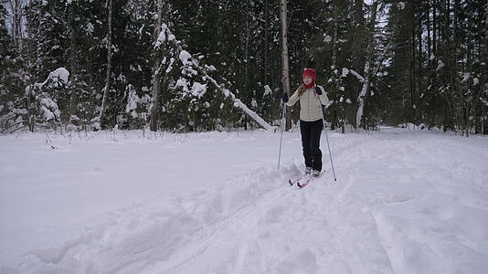 年轻的caucasian微笑的女人在冬天在森林里滑雪视频的预览图