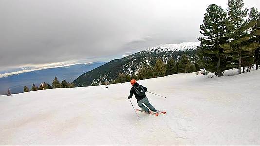 跟踪滑雪者用橙色头盔慢慢地从滑雪坡上划下尾部视频的预览图