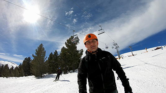 在高山滑雪度假胜地骑着滑雪者在山脚下慢慢游荡视频的预览图