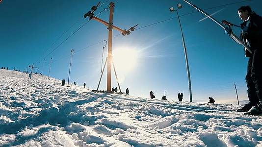 女滑雪者被滑雪电梯拖上山坡在冬季公园的斜坡上慢慢滑雪视频的预览图