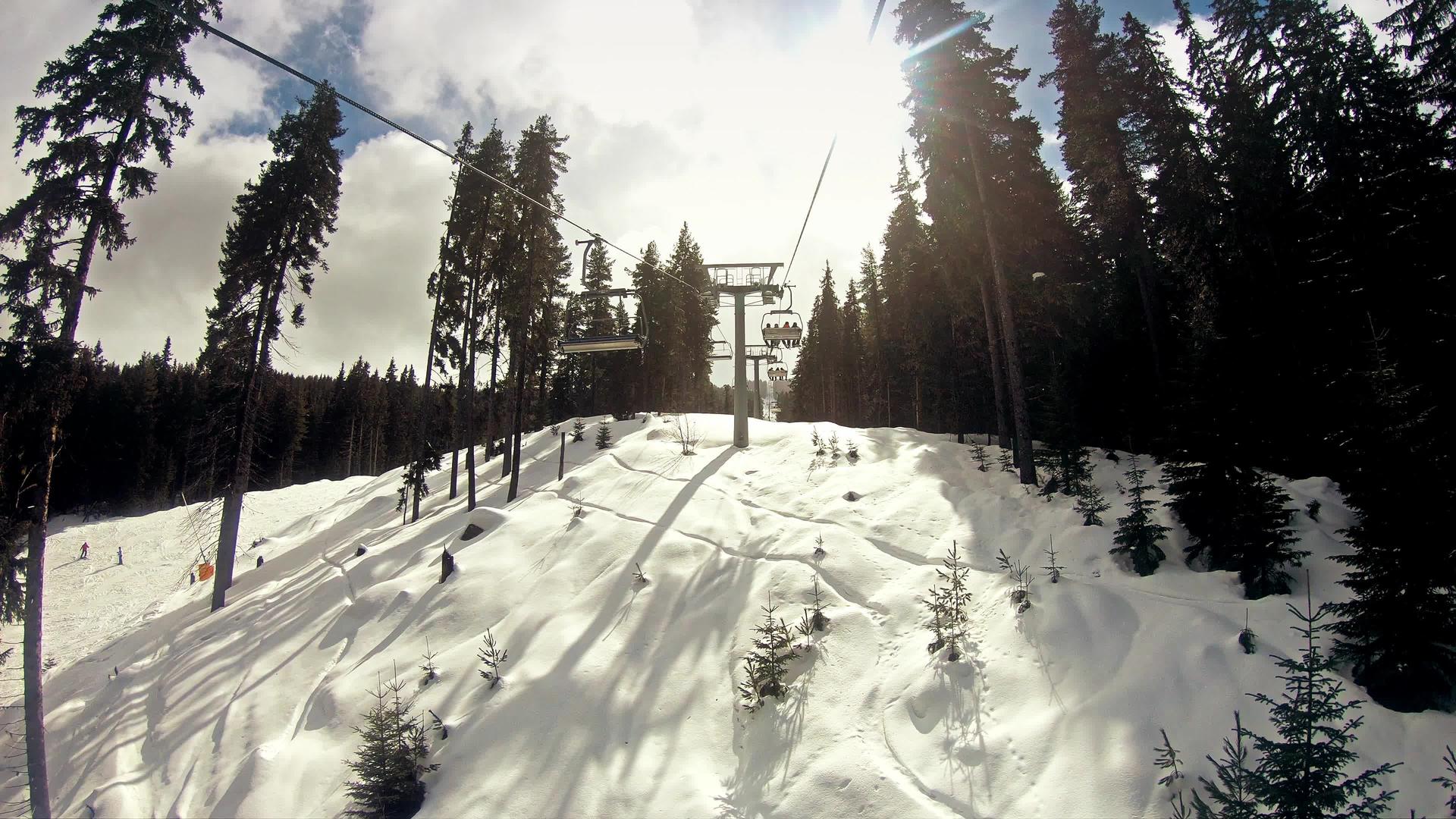 日出时在阳光明媚的冬天滑雪者骑着椅子慢慢地移动电梯视频的预览图