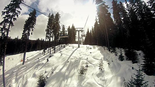 日出时在阳光明媚的冬天滑雪者骑着椅子慢慢地移动电梯视频的预览图