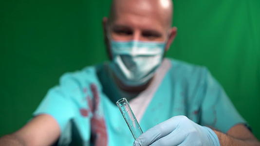 外科医生穿着覆盖着血液的口罩袍用吸管填充试管玻璃容器视频的预览图