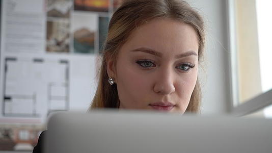 一位迷人的年轻商业女性设计师在她的办公室做笔记本电脑视频的预览图