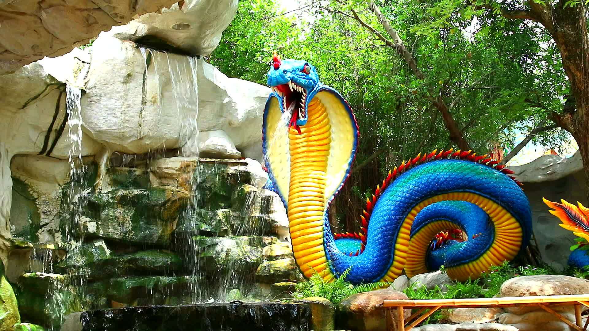 蓝黄黄蛇模型散布在花园瀑布旁边视频的预览图