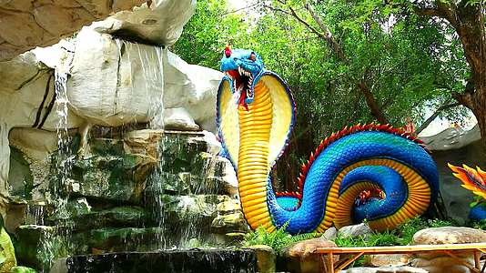 蓝黄黄蛇模型散布在花园瀑布旁边视频的预览图