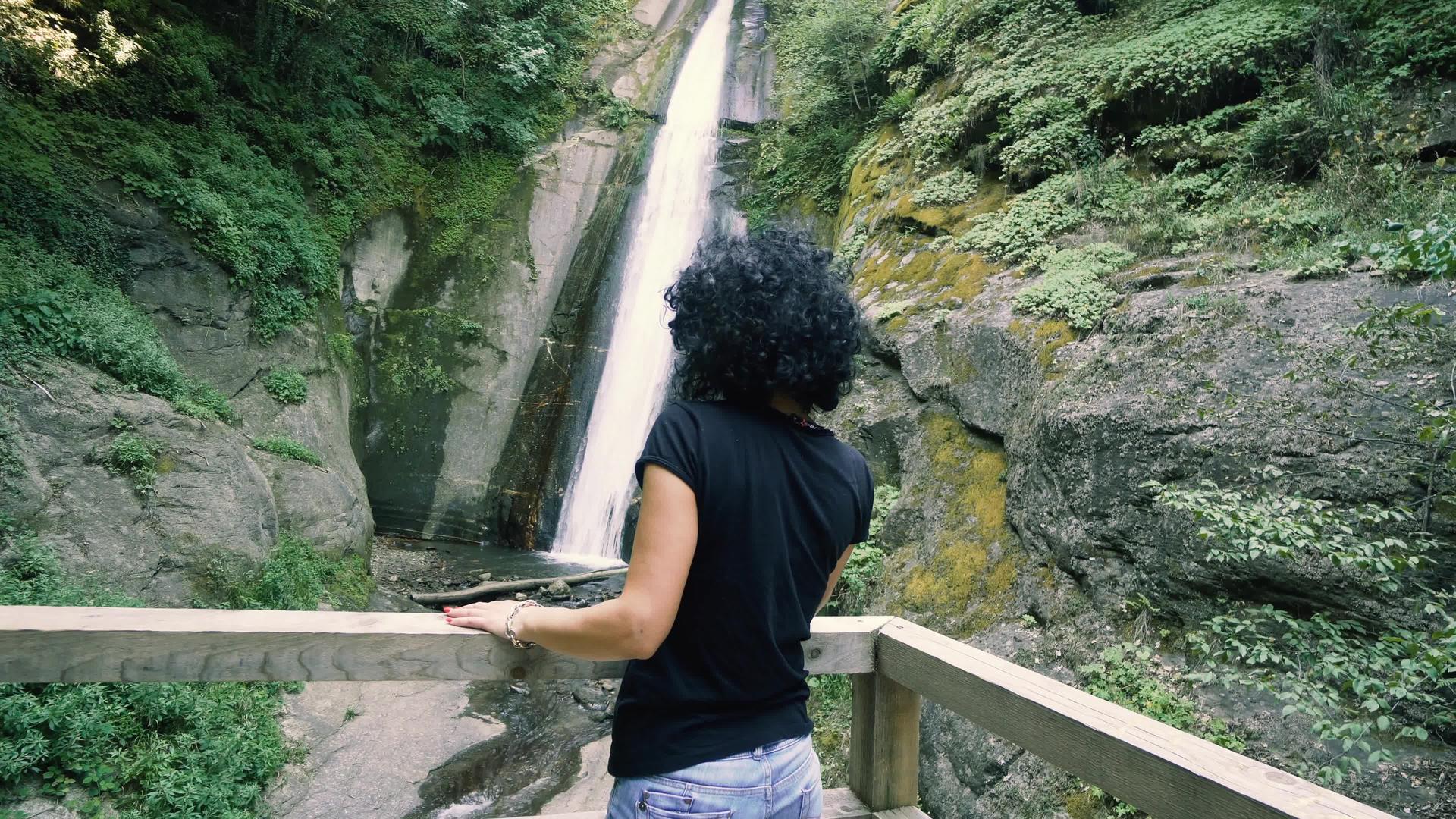 女人享受瀑布的风景视频的预览图