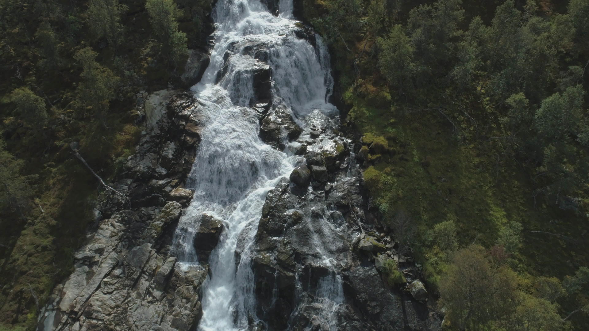 无人机在挪威的瀑布岩石和绿树鸟瞰图上向上飞行视频的预览图