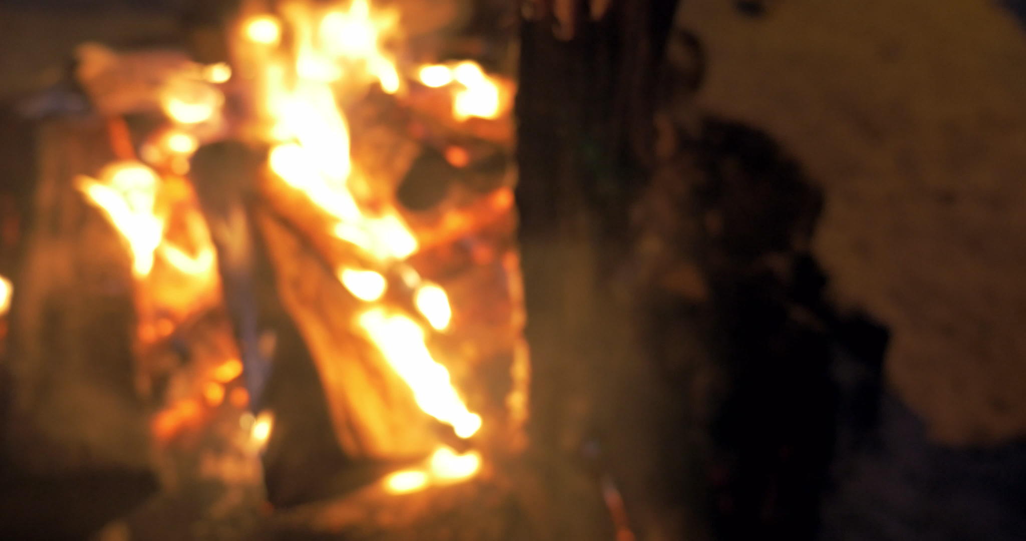 晚上女人把更多的柴火放在火里视频的预览图