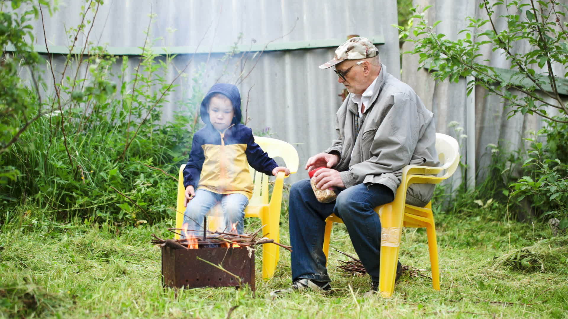 爷爷和孙子坐在户外火炉旁视频的预览图