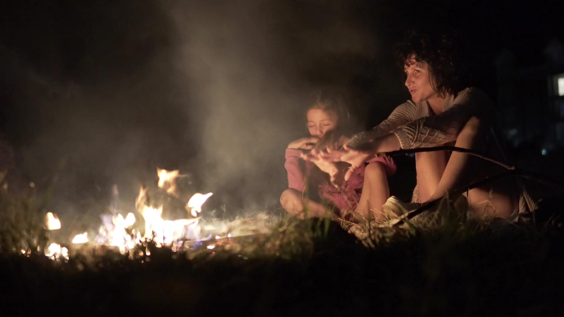 母亲和女儿坐在一个明亮的营火周围视频的预览图