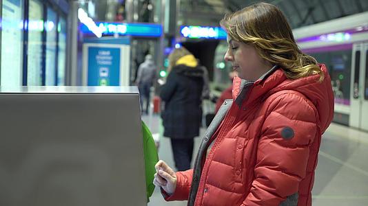 女孩在终点站买票或在火车站使用亚特姆视频的预览图