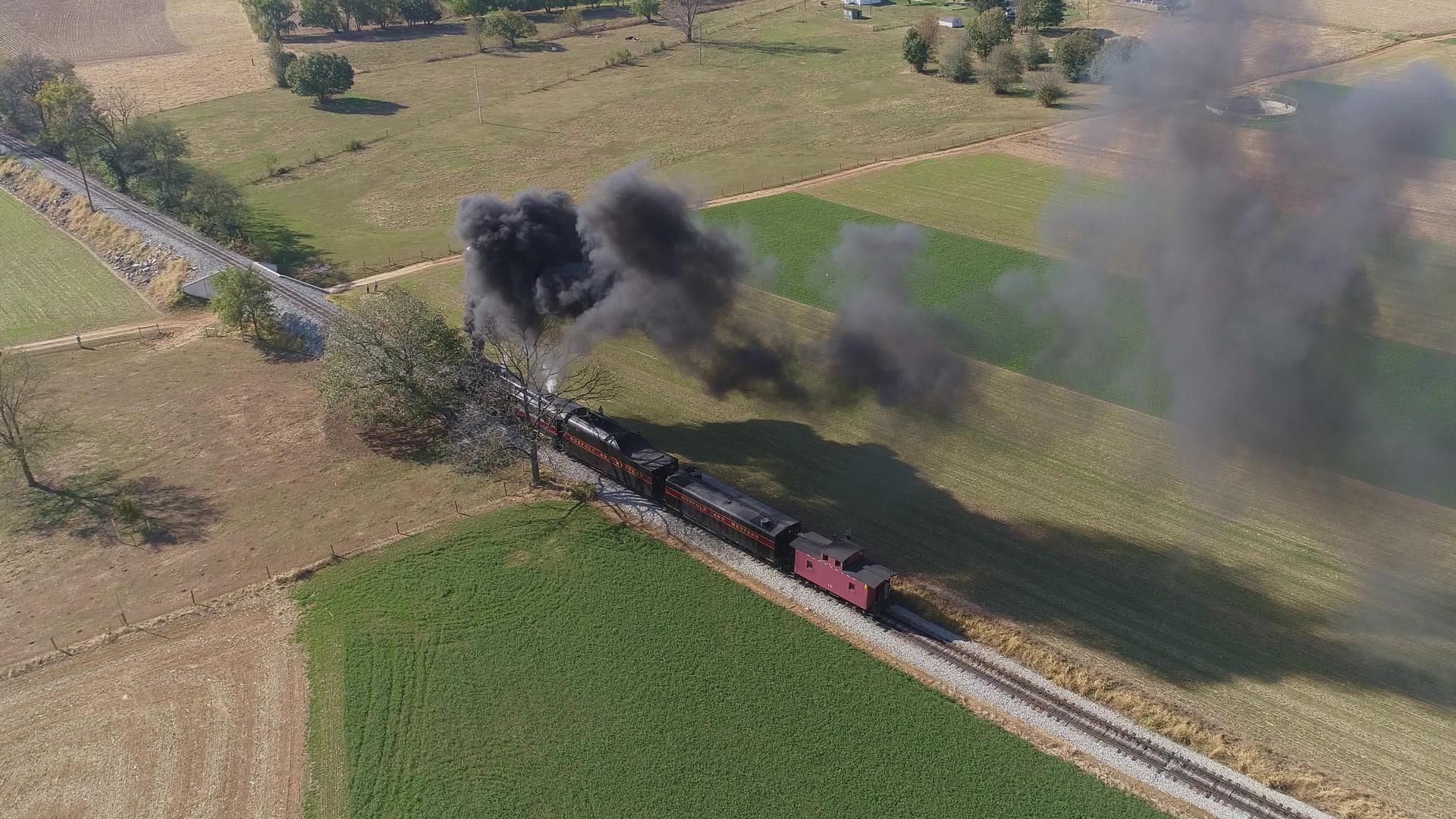 在美丽的秋天吹黑烟和蒸汽时停在乡村的蒸汽火车头部在空中视频的预览图