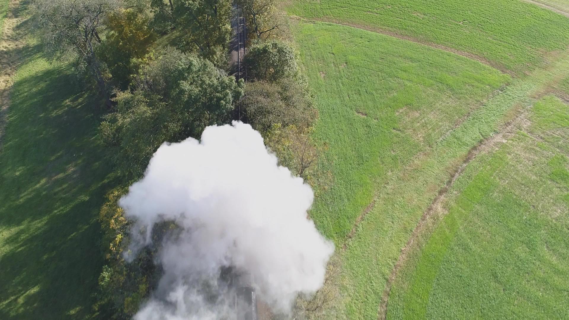 黑烟和蒸汽冲刷树木的恢复蒸汽机车在农村旅行视频的预览图