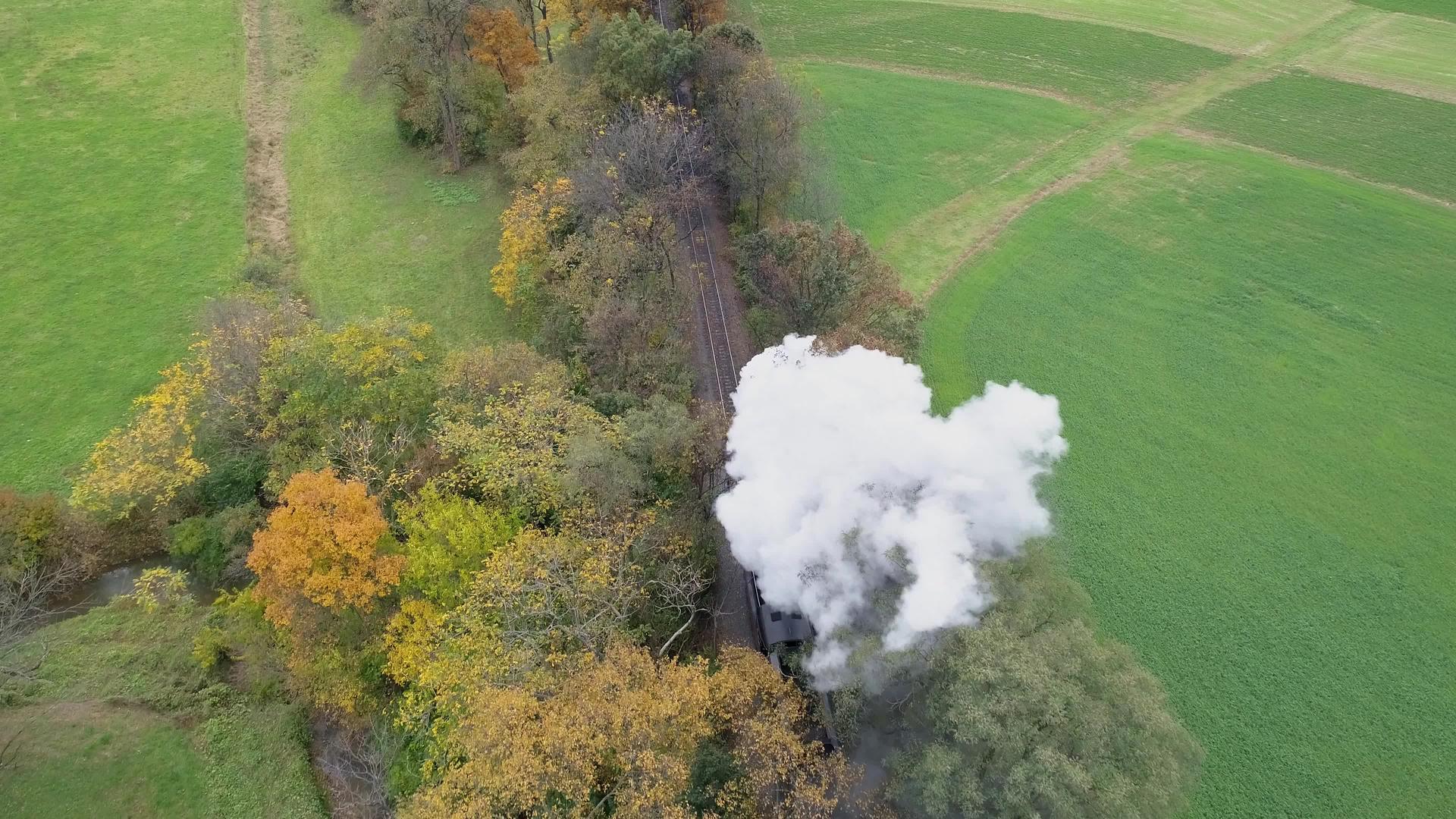 古董头部的空中观察恢复了蒸汽机车旅行秋树当它吹白烟时视频的预览图