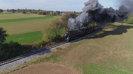 一架经过修复的古董蒸汽机车穿过村庄的空中前部吹着黑烟视频的预览图