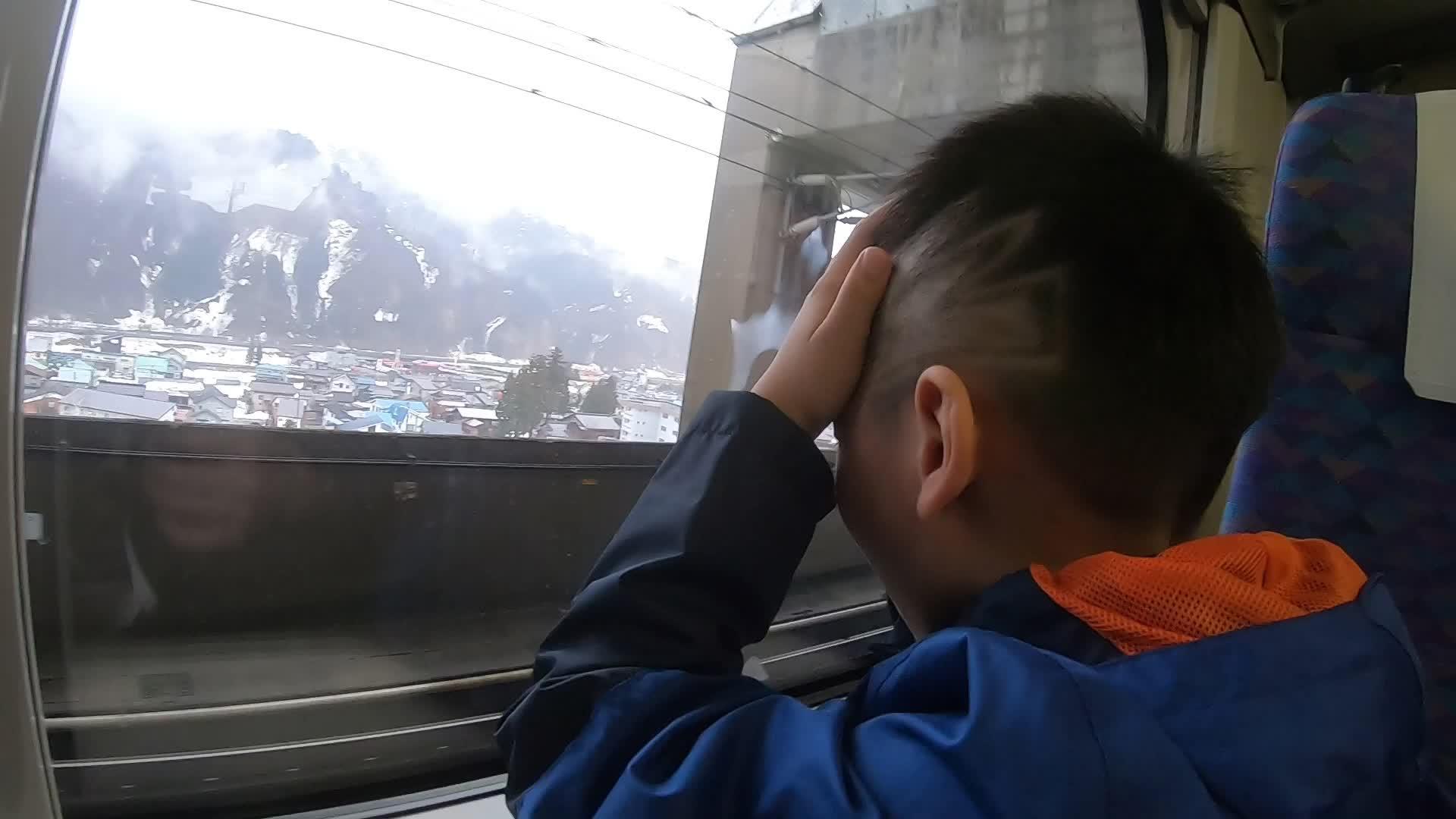 小男孩正在看日本明干火车上的雅潘玉泽雪地度假胜地视频的预览图