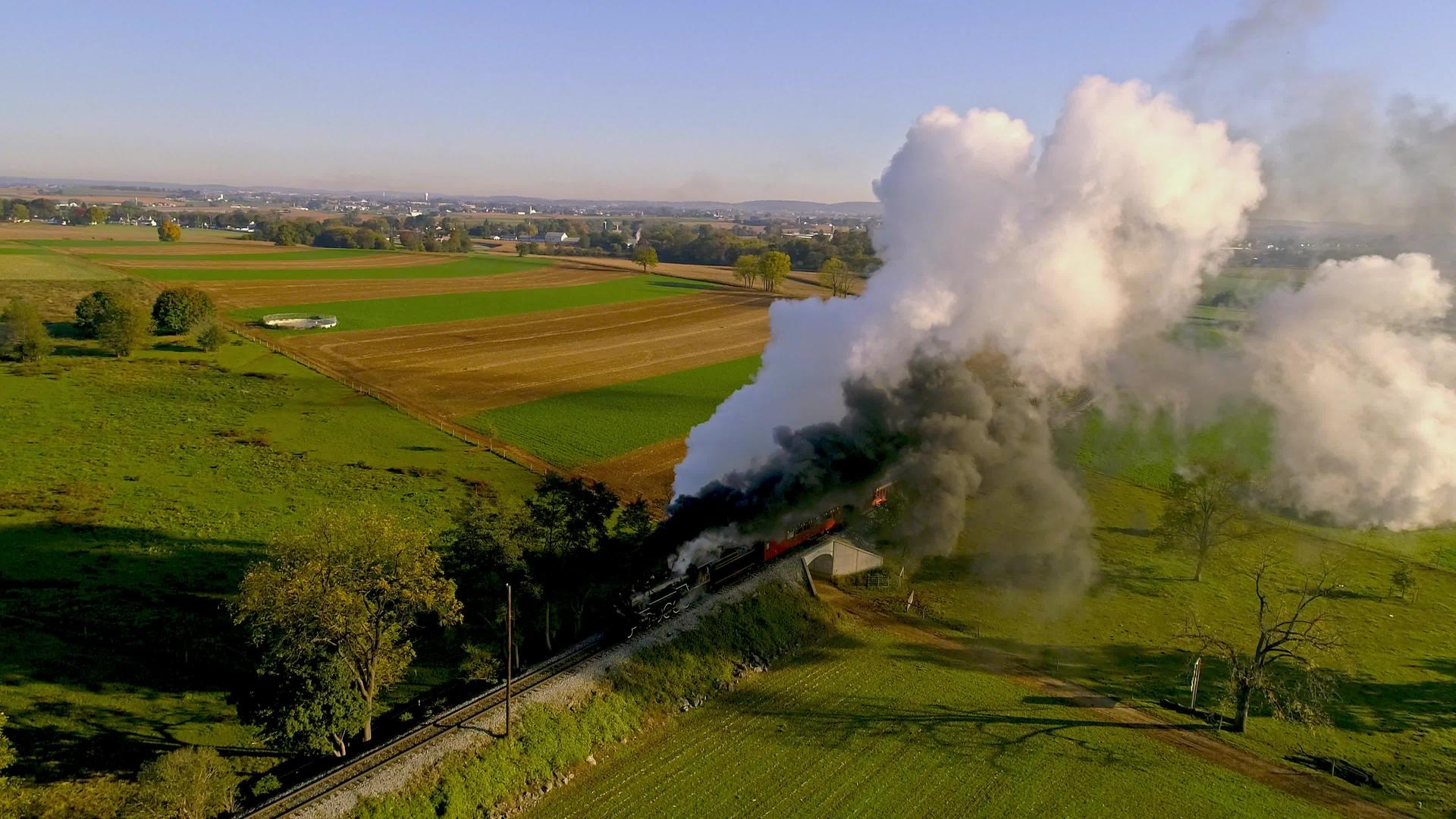 日出时用蒸汽发动机和客运列车在空中观察农田视频的预览图