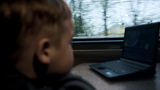 男孩在火车的笔记本电脑上看电影或漫画视频的预览图
