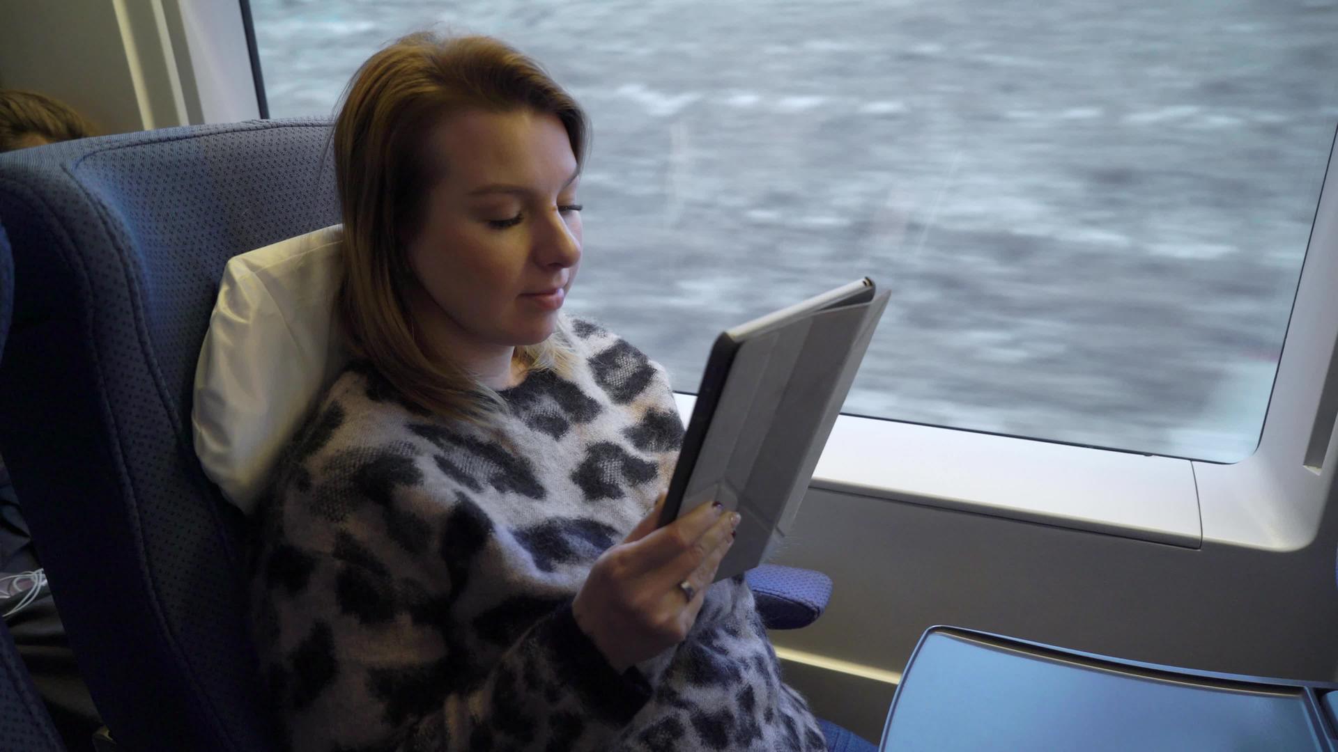 年轻女子在火车上用手持平板电脑工作视频的预览图