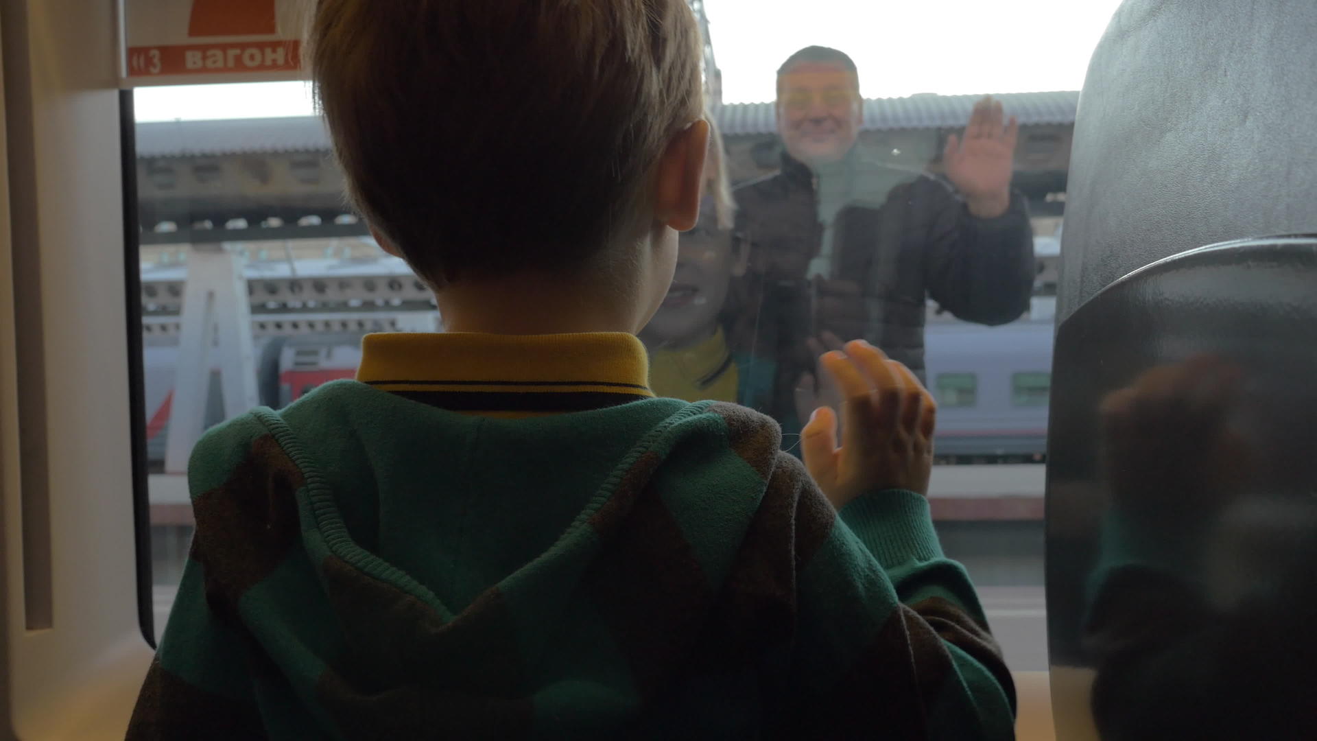 男孩从火车上看着窗外的背影挥舞着双臂向祖父母道别视频的预览图