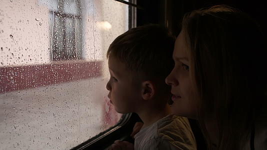 母亲和儿子在雨天看着窗外的火车视频的预览图