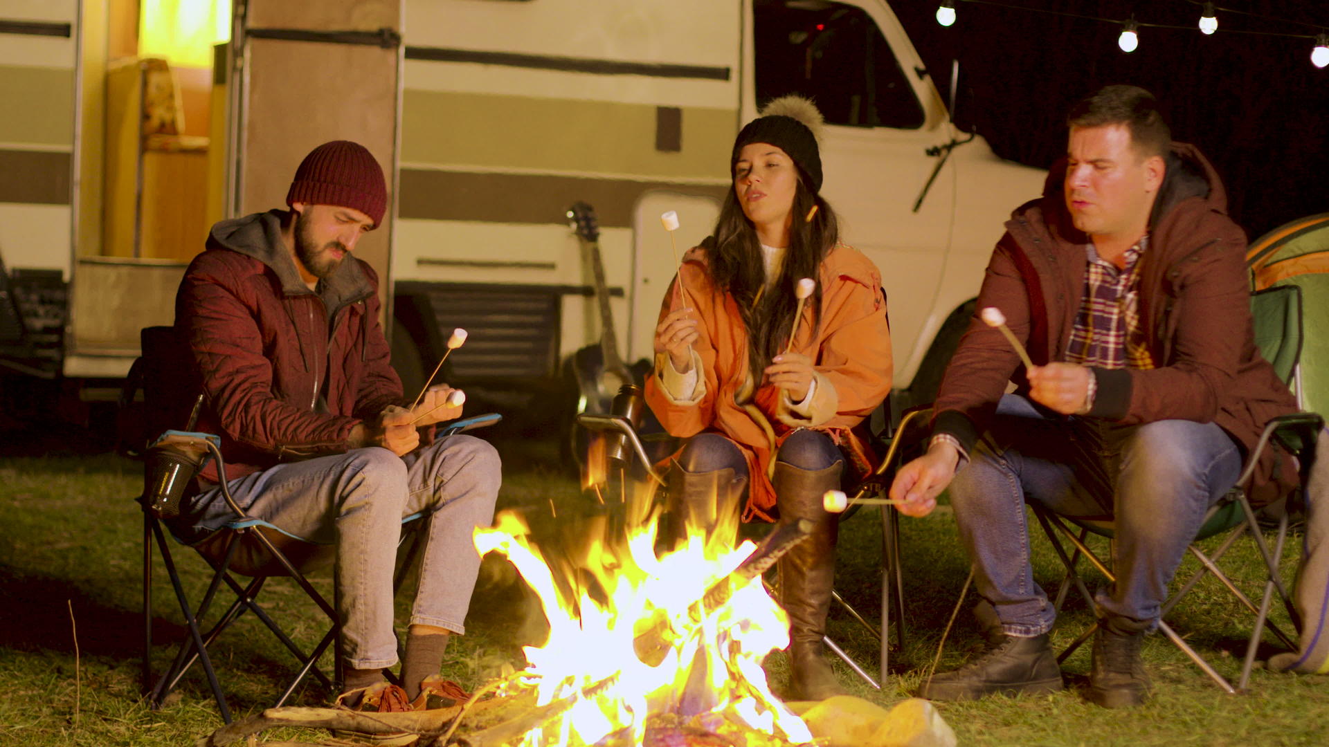 朋友们在露营的炉子周围放松用棍子烤棉花糖视频的预览图