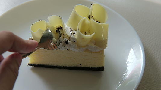 用手把美味的白巧克力蛋糕切成甜点放在白色的盘子上视频的预览图
