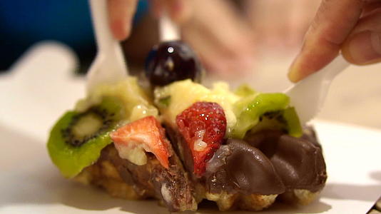 在达尼面包店用塑料刀切巧克力涂面华夫饼和水果粉视频的预览图