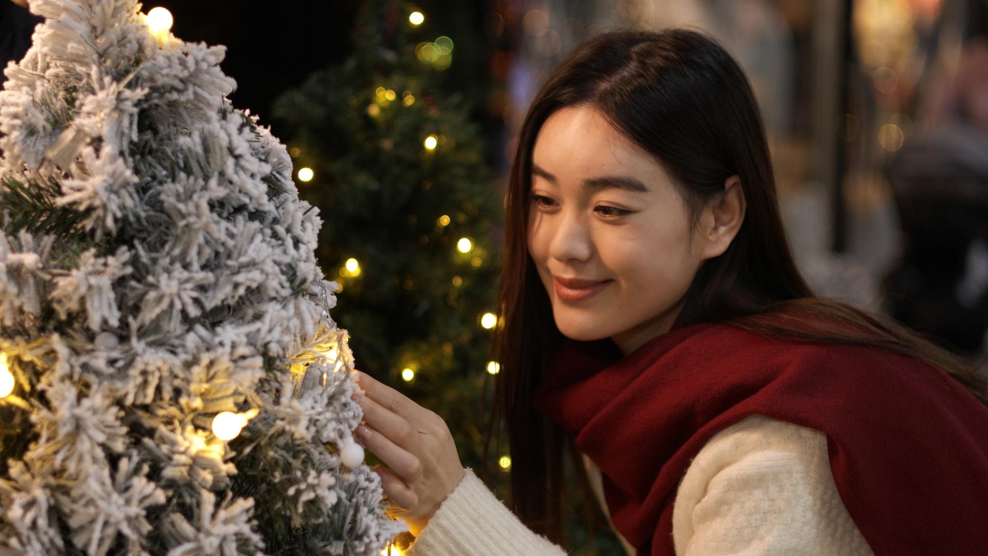 女生被圣诞树上的小彩灯吸引视频的预览图
