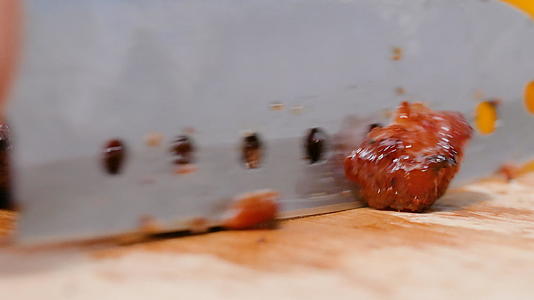用刀把烧烤猪肉切在厨房的木板上视频的预览图
