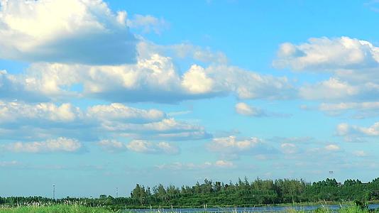 美丽的蓝天和白云在湖泊和田野中缓慢移动视频的预览图
