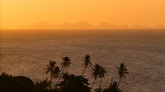 壮丽的热带橙色夏季海洋实时日落和海洋山脉剪影视频的预览图