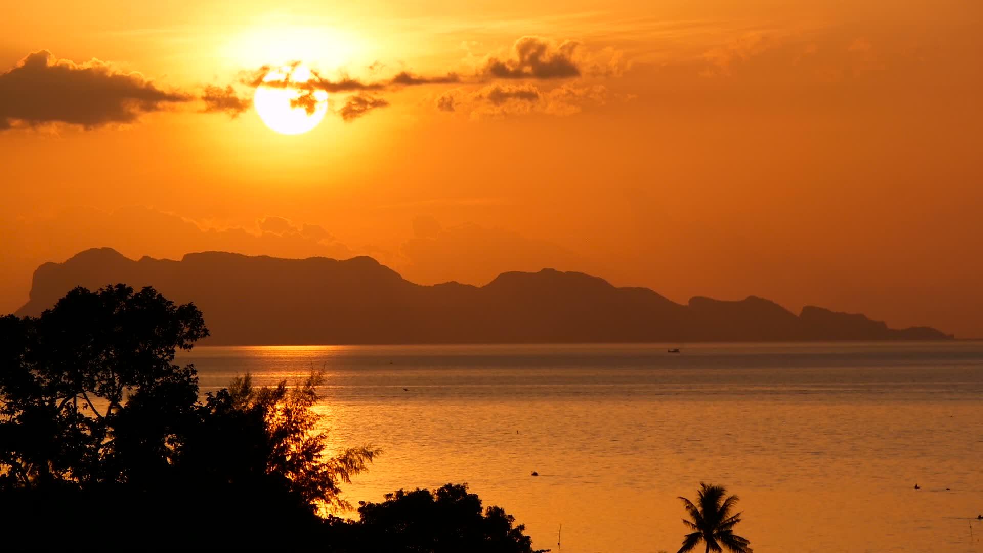 壮丽的热带橙色夏季海洋实时日落和海洋山脉剪影视频的预览图