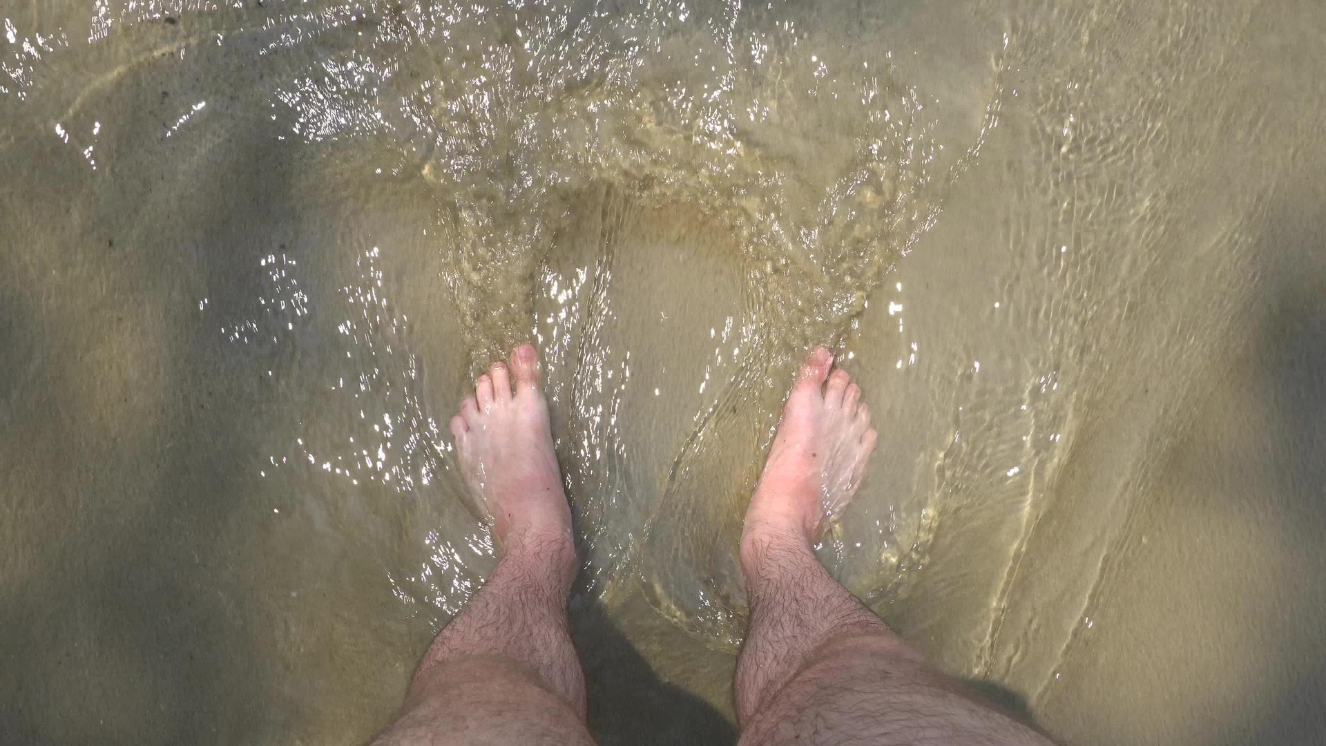 男人的脚在海里被海浪冲洗视频的预览图
