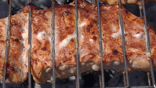 美味多汁的猪肉牛排在木炭烧烤炉上使用含有火烟的金属叉视频的预览图