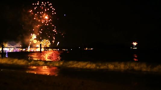 明亮的金色烟花在海面上空的夜空中爆炸视频的预览图
