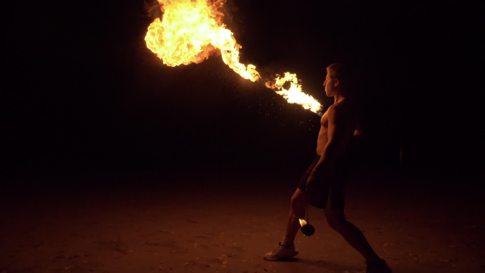 年轻人在火炬上喷洒煤油和爆燃的火焰展示慢动作视频的预览图