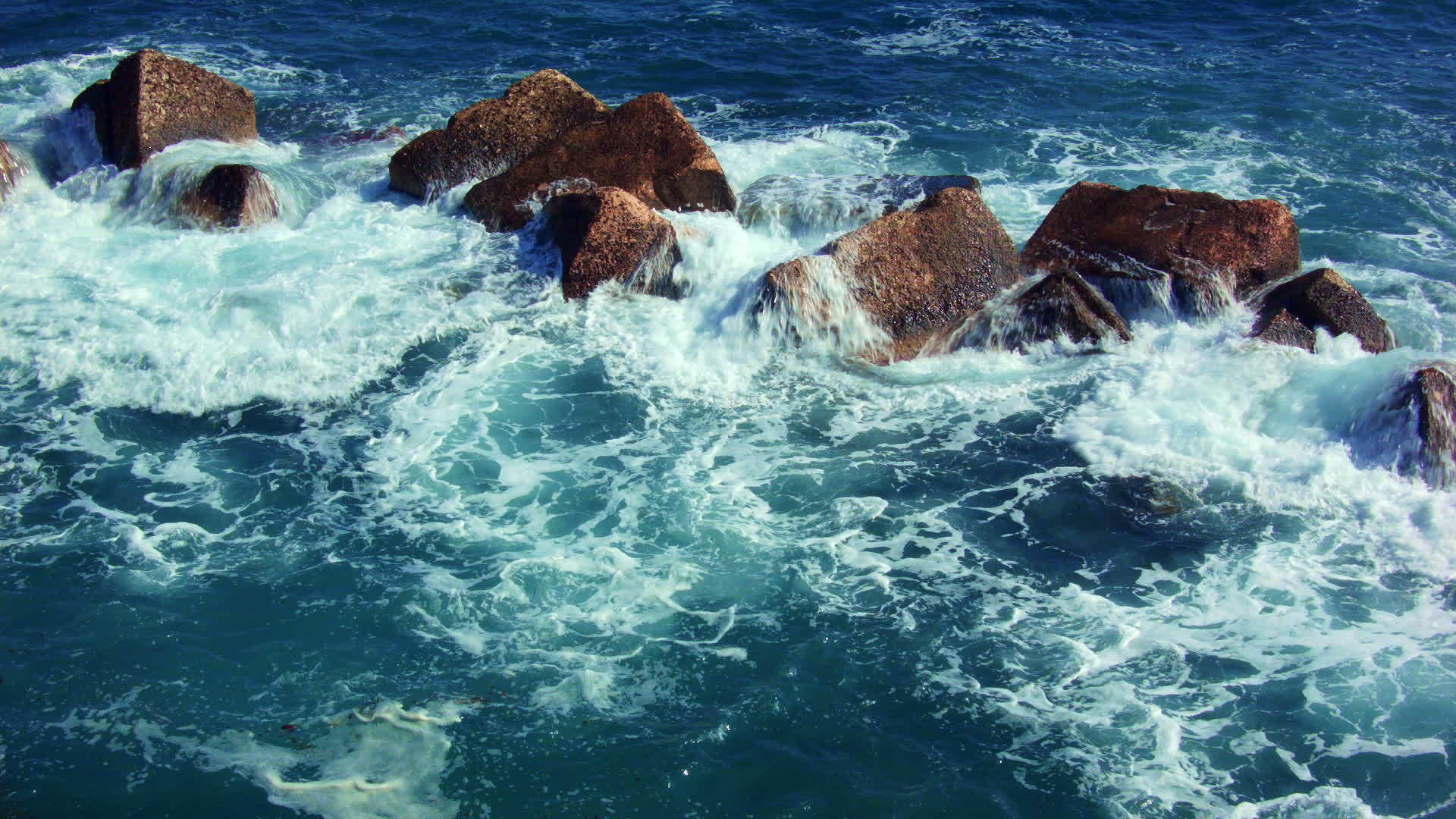 深绿色的海浪落在深红色的岩石上视频的预览图