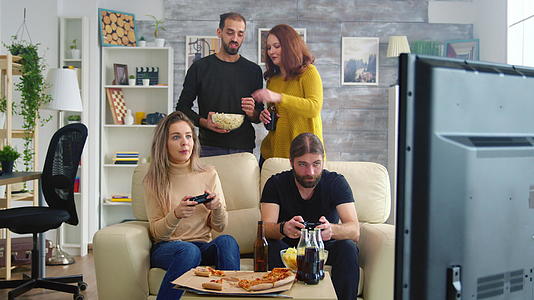 年轻夫妇吃爆米花但他们的朋友在玩电子游戏视频的预览图