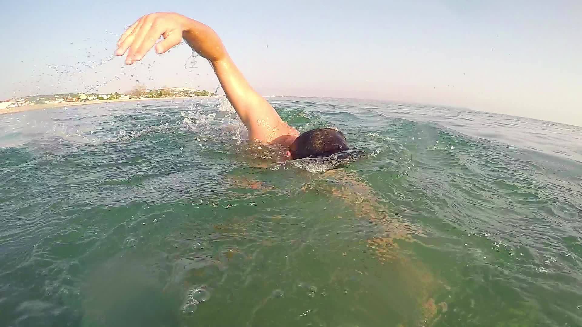 年轻人在湖中游泳和爬行跟着一个游泳者冲向镜头视频的预览图
