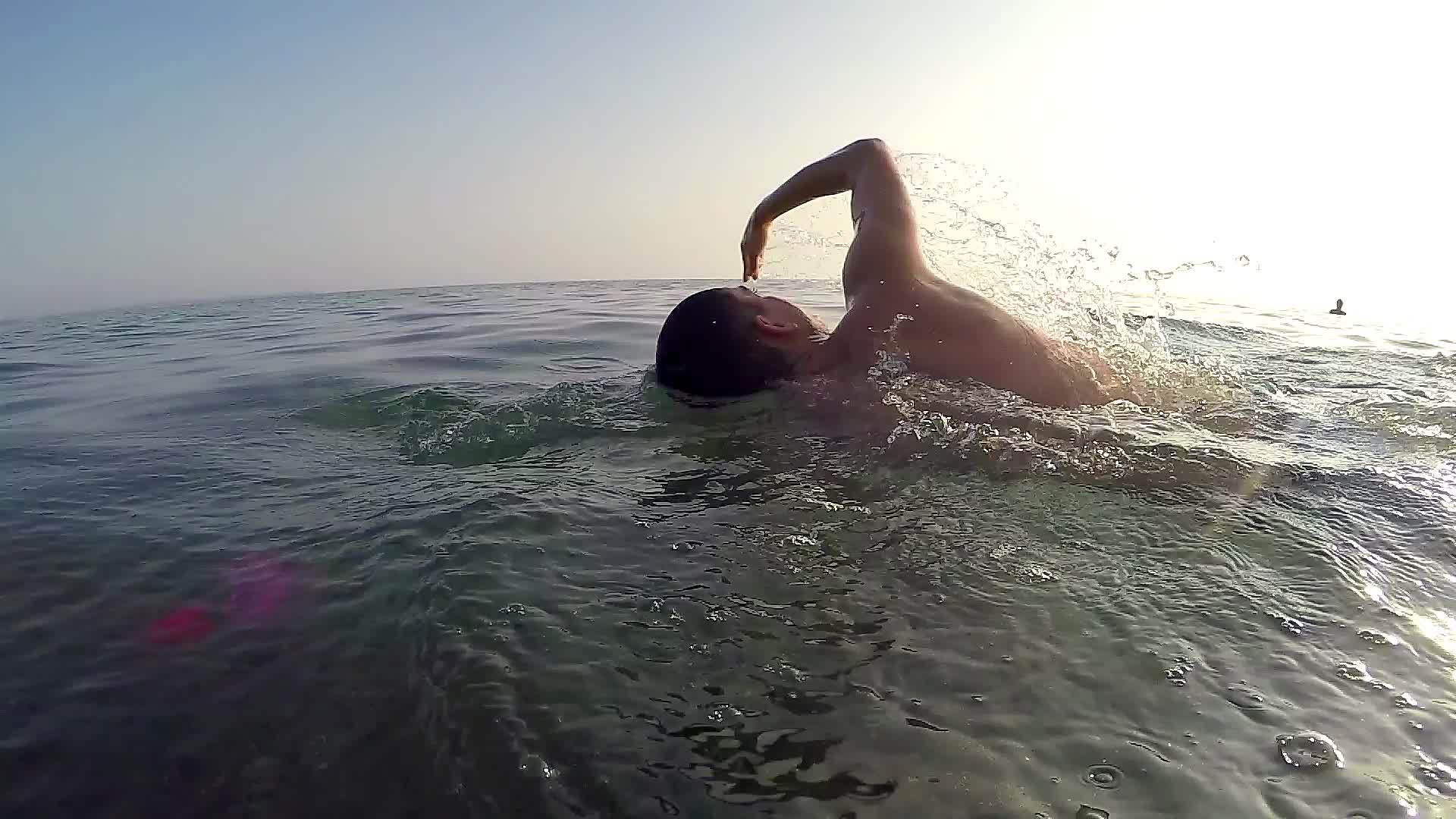 运动男子在前面游泳在日落马拉松上爬行拍摄后慢动作视频的预览图
