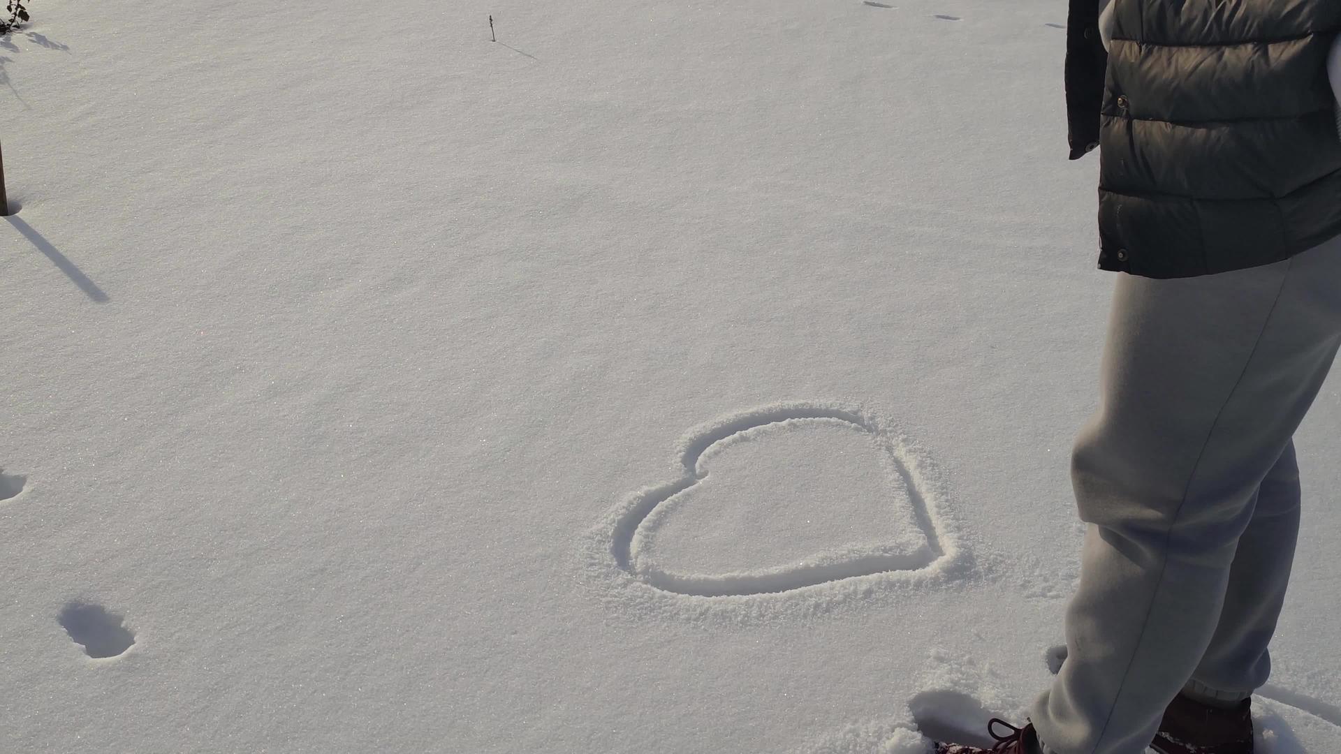 女人在冬天的雪雪上画了一颗心视频的预览图