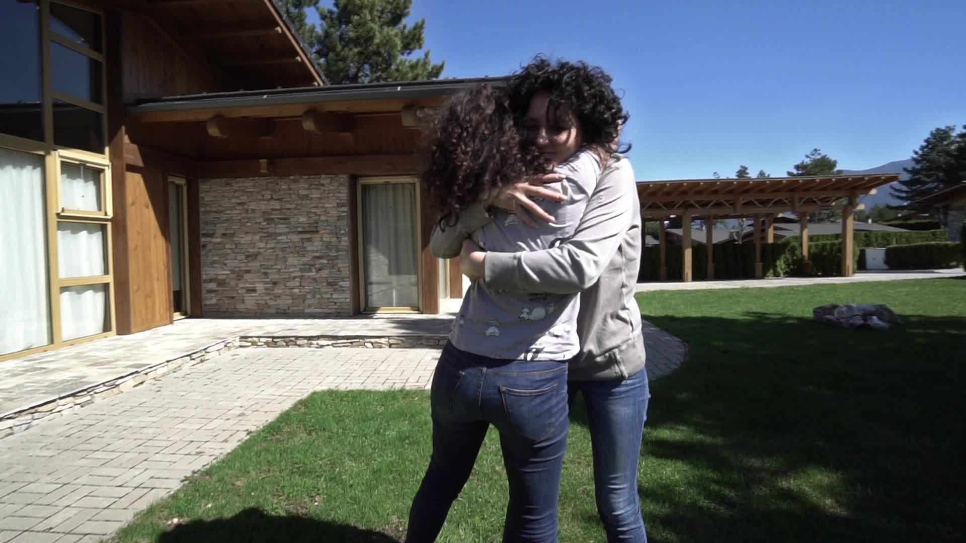 当两个女人在豪华住宅前相遇时她们互相拥抱互相亲吻慢慢移动视频的预览图