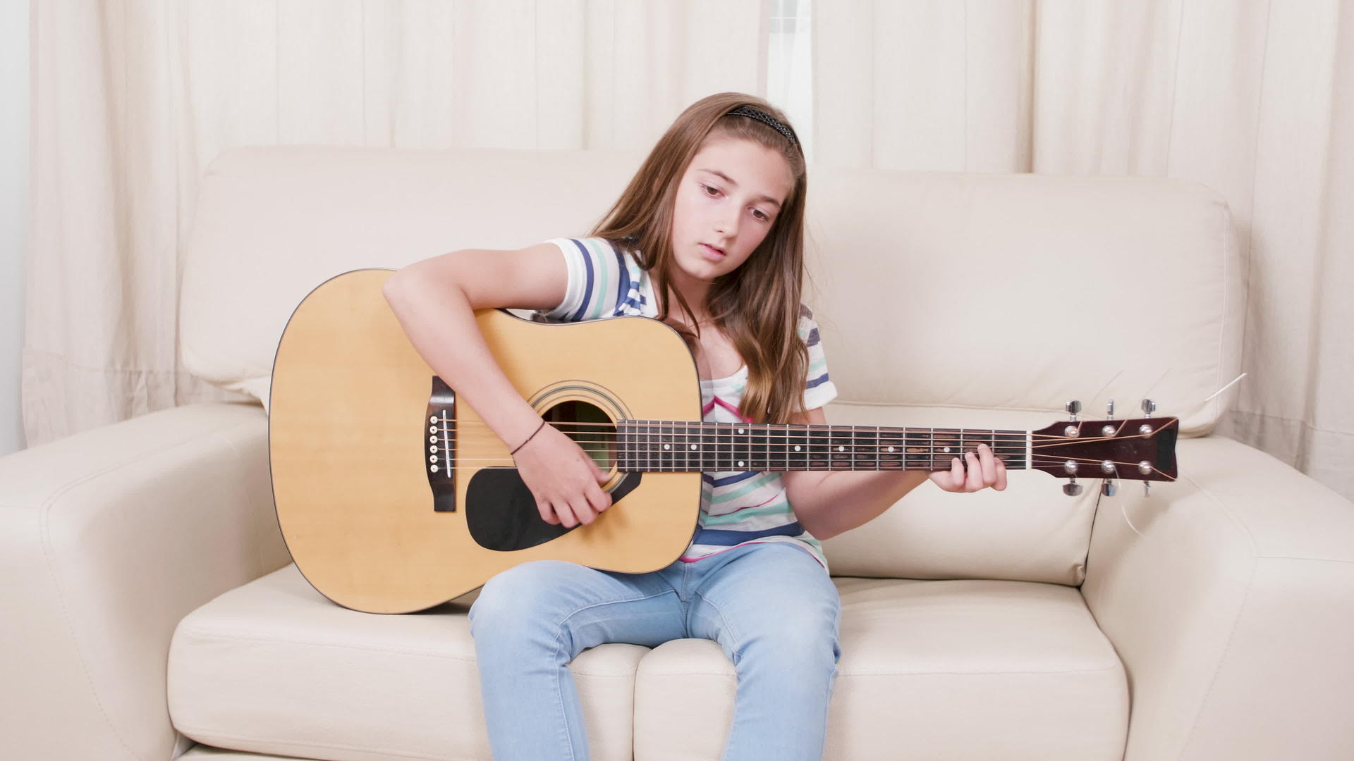 女孩在客厅里学习弹六弦吉他视频的预览图