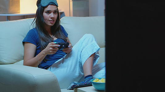 女人坐在沙发上玩电子游戏视频的预览图